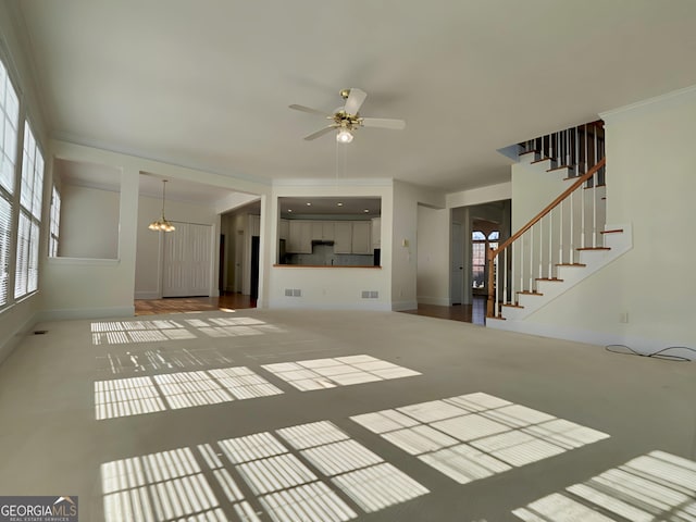 unfurnished living room with visible vents, stairway, baseboards, and ceiling fan with notable chandelier