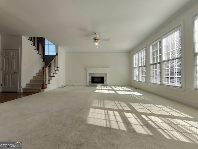 unfurnished living room featuring baseboards, a ceiling fan, carpet, stairs, and a high end fireplace