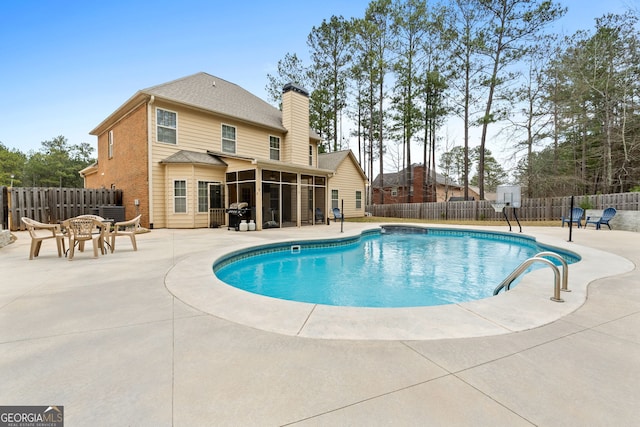 view of swimming pool featuring a patio area, a fenced backyard, a sunroom, and a fenced in pool