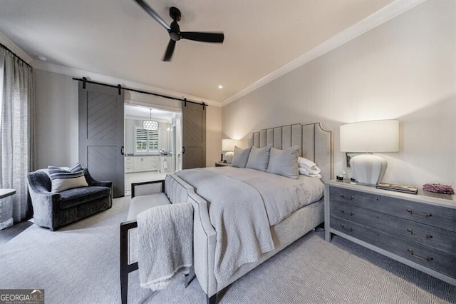 bedroom featuring a barn door, ensuite bath, ceiling fan, ornamental molding, and carpet floors