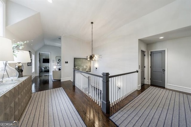 hallway with baseboards, vaulted ceiling, an inviting chandelier, and wood finished floors