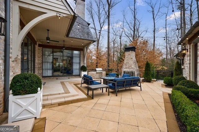 view of patio / terrace featuring a ceiling fan, area for grilling, fence, and an outdoor living space with a fireplace