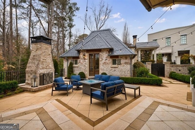 view of patio featuring an outdoor living space with a fireplace, a gate, and fence