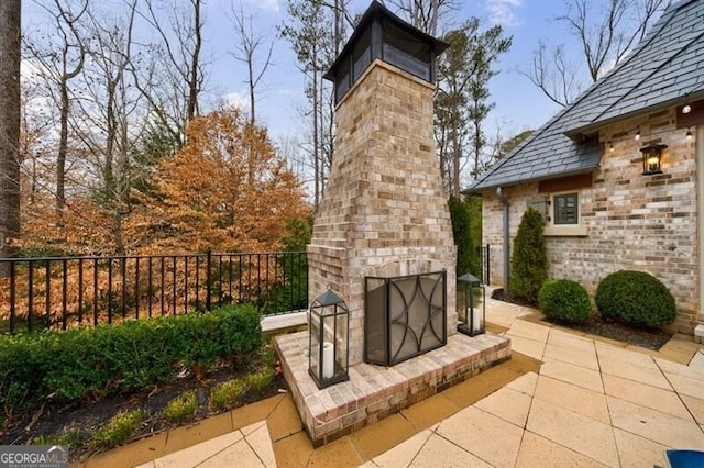 view of patio / terrace with an outdoor brick fireplace and fence