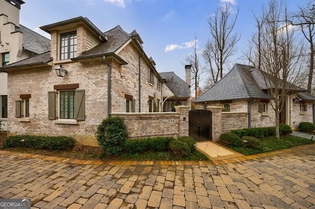 view of home's exterior featuring a gate, brick siding, and fence