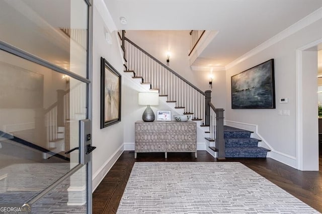 foyer entrance with ornamental molding, baseboards, and stairs