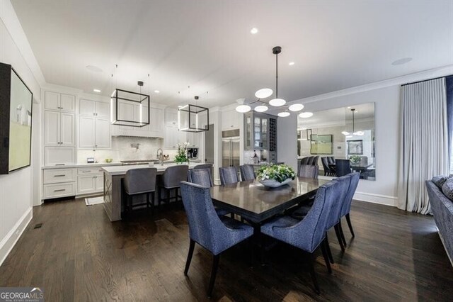 dining area featuring dark wood-style flooring, crown molding, a lit fireplace, and baseboards