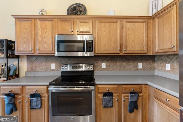 kitchen featuring light countertops, appliances with stainless steel finishes, brown cabinets, and decorative backsplash