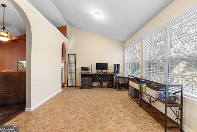 tiled office space featuring a ceiling fan, arched walkways, vaulted ceiling, and baseboards