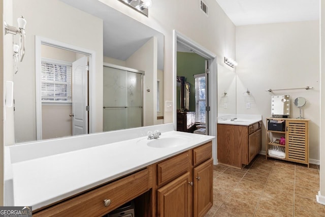 full bathroom with two vanities, a sink, visible vents, a healthy amount of sunlight, and a stall shower