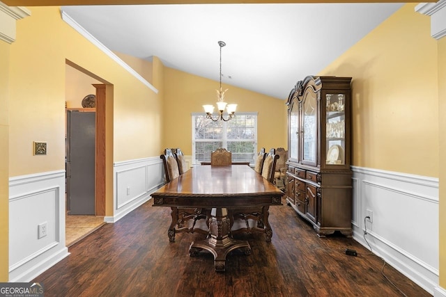 dining space featuring a chandelier, a wainscoted wall, lofted ceiling, and dark wood-style floors