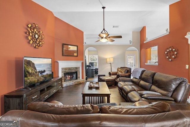 living area with visible vents, arched walkways, dark wood-style floors, ceiling fan, and a fireplace