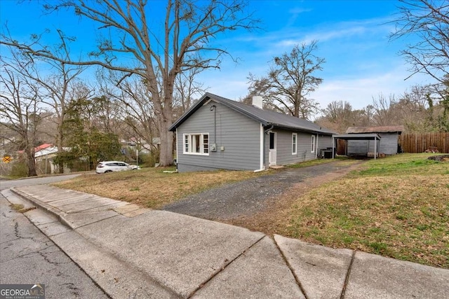 view of home's exterior featuring a chimney, a yard, and fence