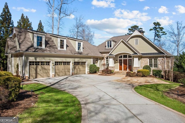 view of front facade with driveway, stone siding, a shingled roof, and a garage