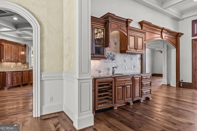 bar featuring arched walkways, beverage cooler, coffered ceiling, a sink, and beamed ceiling