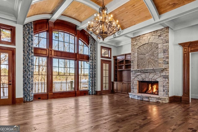 unfurnished living room featuring wood-type flooring, plenty of natural light, a stone fireplace, and baseboards