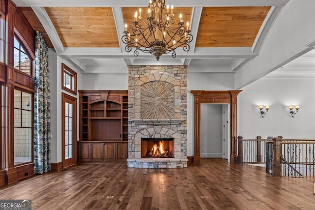 unfurnished living room with beamed ceiling, a stone fireplace, and hardwood / wood-style floors