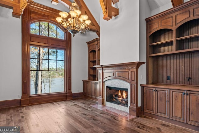 unfurnished living room featuring baseboards, built in features, dark wood-style floors, a fireplace with flush hearth, and high vaulted ceiling