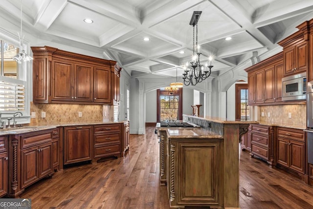 kitchen with appliances with stainless steel finishes, arched walkways, dark wood-type flooring, and a sink