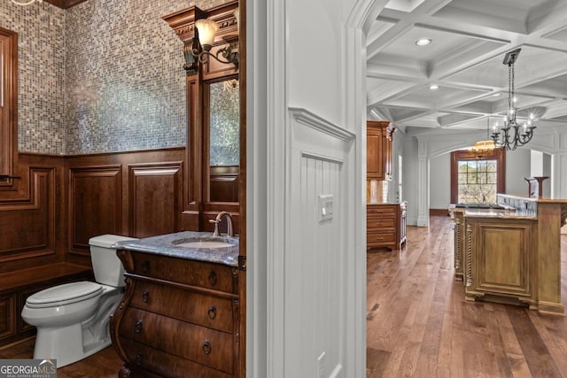 bathroom with toilet, hardwood / wood-style flooring, coffered ceiling, vanity, and beam ceiling