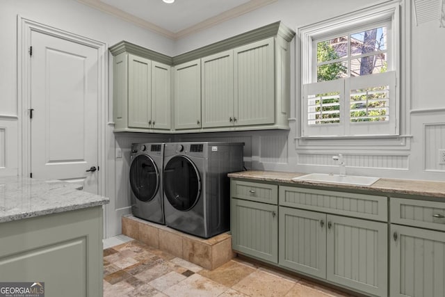 washroom featuring washer and clothes dryer, a sink, cabinet space, stone finish floor, and crown molding