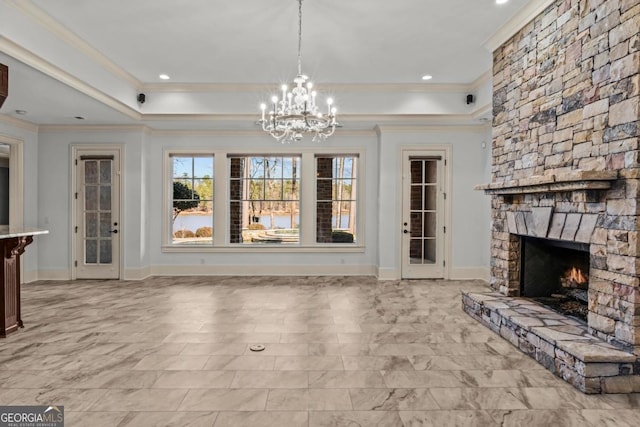 unfurnished living room with baseboards, a raised ceiling, an inviting chandelier, crown molding, and a stone fireplace