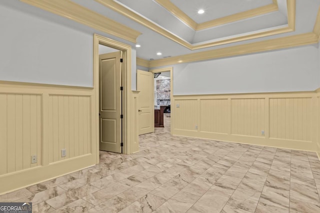 empty room featuring a tray ceiling, marble finish floor, a wainscoted wall, recessed lighting, and ornamental molding