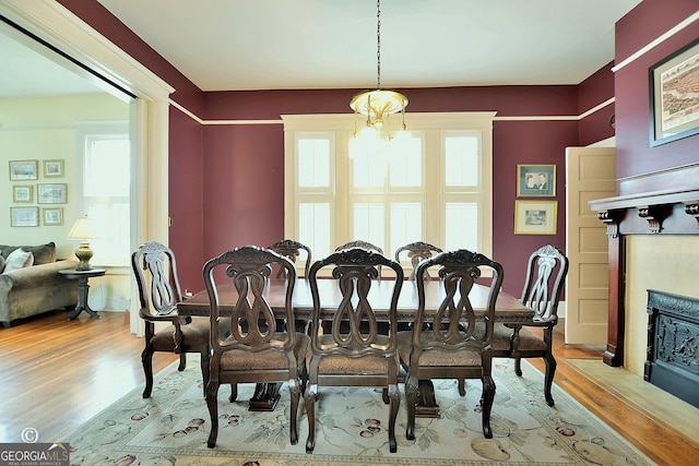 dining area with an inviting chandelier, a fireplace with flush hearth, and wood finished floors