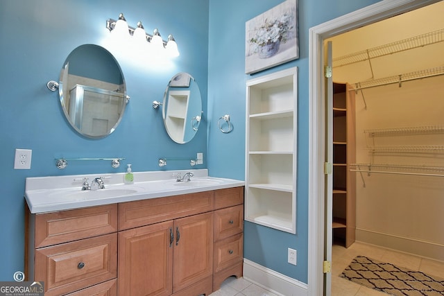 full bath with tile patterned floors, a sink, a walk in closet, and a shower stall