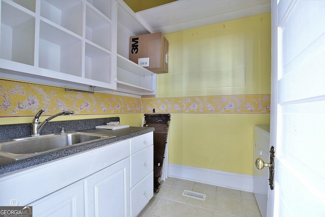 kitchen featuring light tile patterned floors, open shelves, dark countertops, visible vents, and a sink