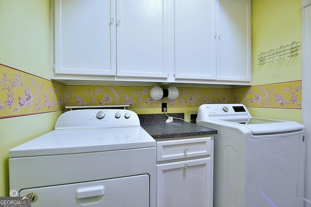 clothes washing area featuring washer and dryer, cabinet space, and wallpapered walls