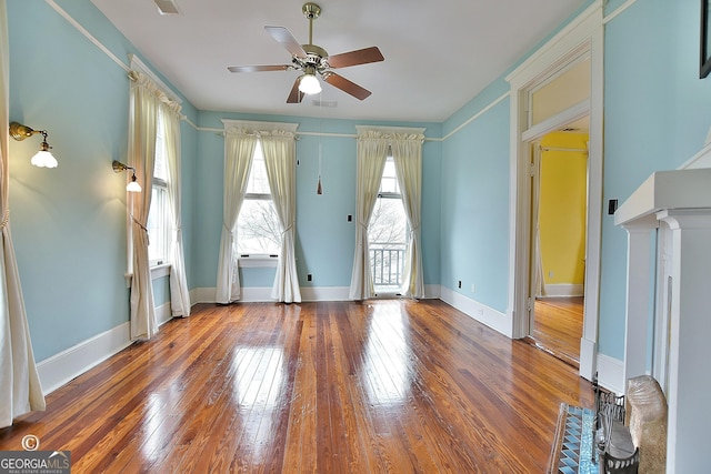 interior space with a ceiling fan, baseboards, visible vents, and hardwood / wood-style floors