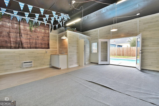 interior space featuring wood finished floors, a wall unit AC, carpet flooring, and wooden walls