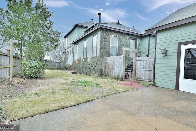 view of side of home featuring a fenced backyard and a patio