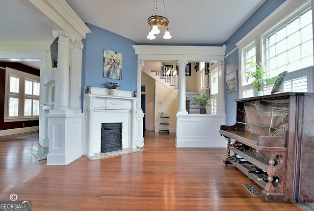 sitting room with a healthy amount of sunlight, decorative columns, and wood finished floors