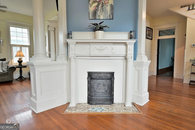 details with a fireplace with flush hearth, wood finished floors, and decorative columns