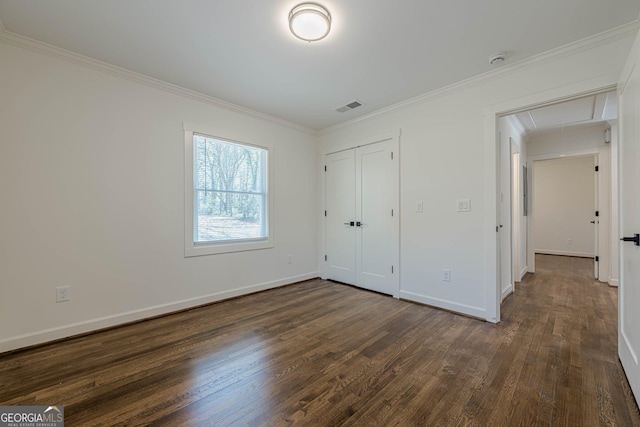 unfurnished bedroom featuring visible vents, baseboards, dark wood finished floors, attic access, and crown molding