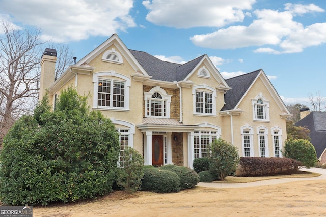 view of front of home featuring stone siding, a chimney, and stucco siding