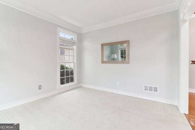 carpeted empty room with baseboards, visible vents, and crown molding