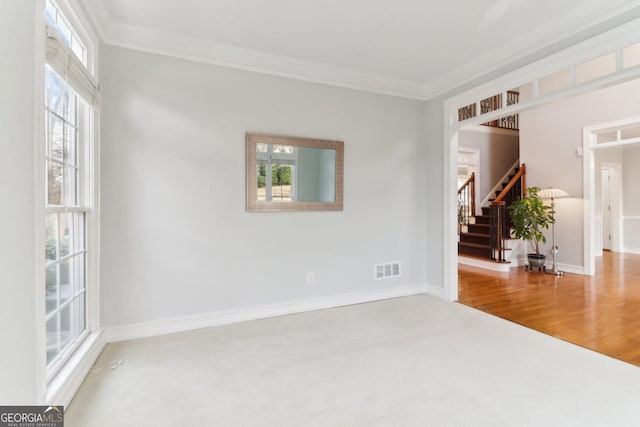 empty room with a wealth of natural light, crown molding, and stairs