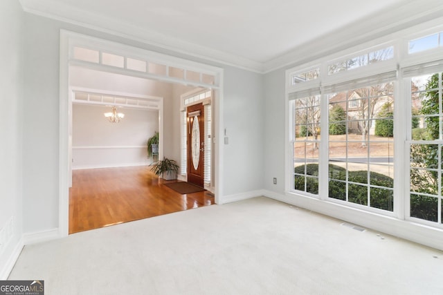 carpeted spare room with crown molding, baseboards, visible vents, and a notable chandelier