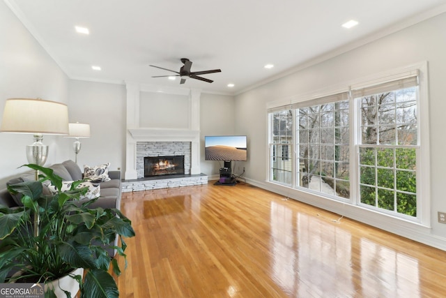 living area featuring ornamental molding, a fireplace, wood finished floors, and recessed lighting