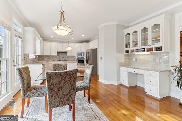 dining area featuring ornamental molding, visible vents, built in desk, and light wood finished floors