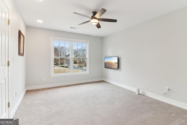 carpeted spare room featuring baseboards, visible vents, and ceiling fan