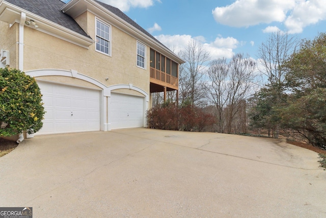 view of home's exterior with an attached garage, roof with shingles, concrete driveway, and stucco siding