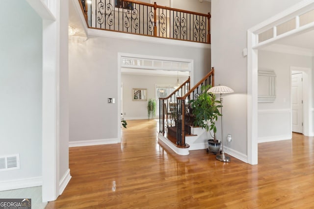 entryway with stairs, wood finished floors, visible vents, and baseboards