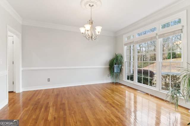 unfurnished dining area featuring ornamental molding, visible vents, a notable chandelier, and wood finished floors