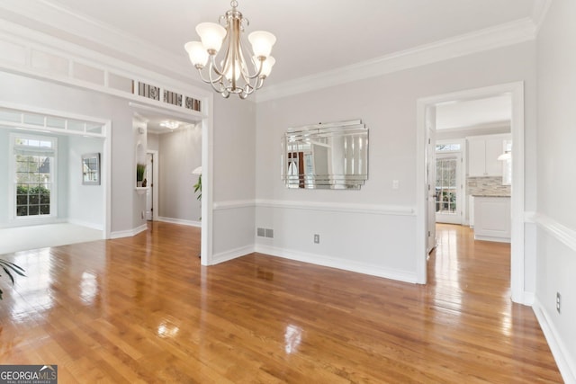 unfurnished dining area with a notable chandelier, visible vents, light wood-style floors, ornamental molding, and baseboards