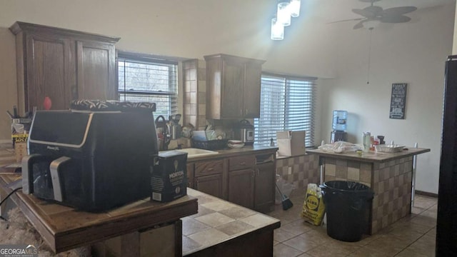 kitchen featuring ceiling fan, tile counters, a sink, and tile patterned floors