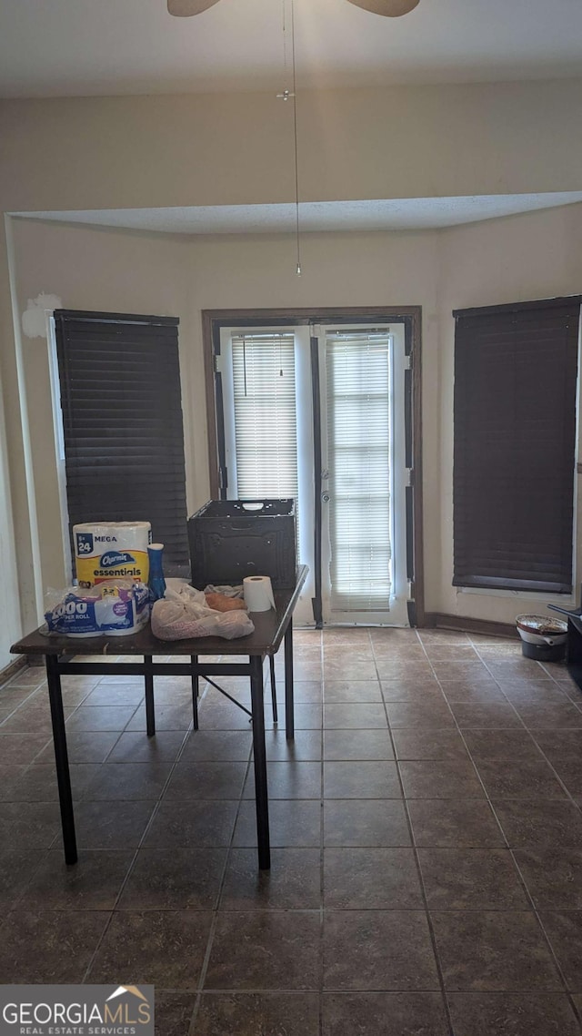 dining space with ceiling fan and dark tile patterned floors